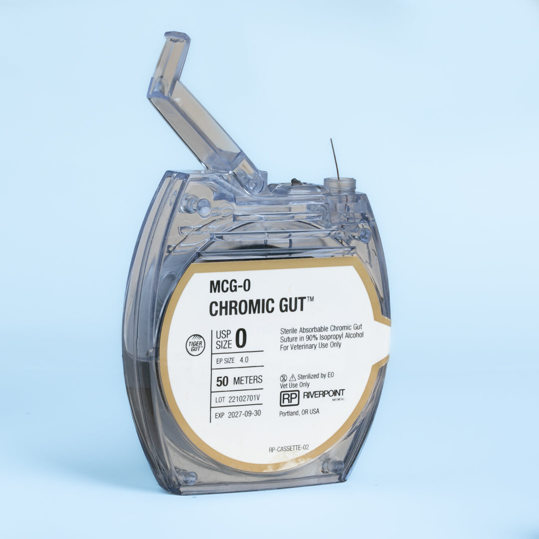 Image of RIVERPOINT's MCG-0 Chromic Gut suture in a clear, round cassette, showcasing a 50-meter length of violet-colored suture. The label indicates size 0, sterilization by gamma irradiation, and key features like superior knot security and smooth surface. The packaging is designed for veterinary use, highlighting the suture's optimized collagen purity and chromium salt treatment for predictable strength and absorption.